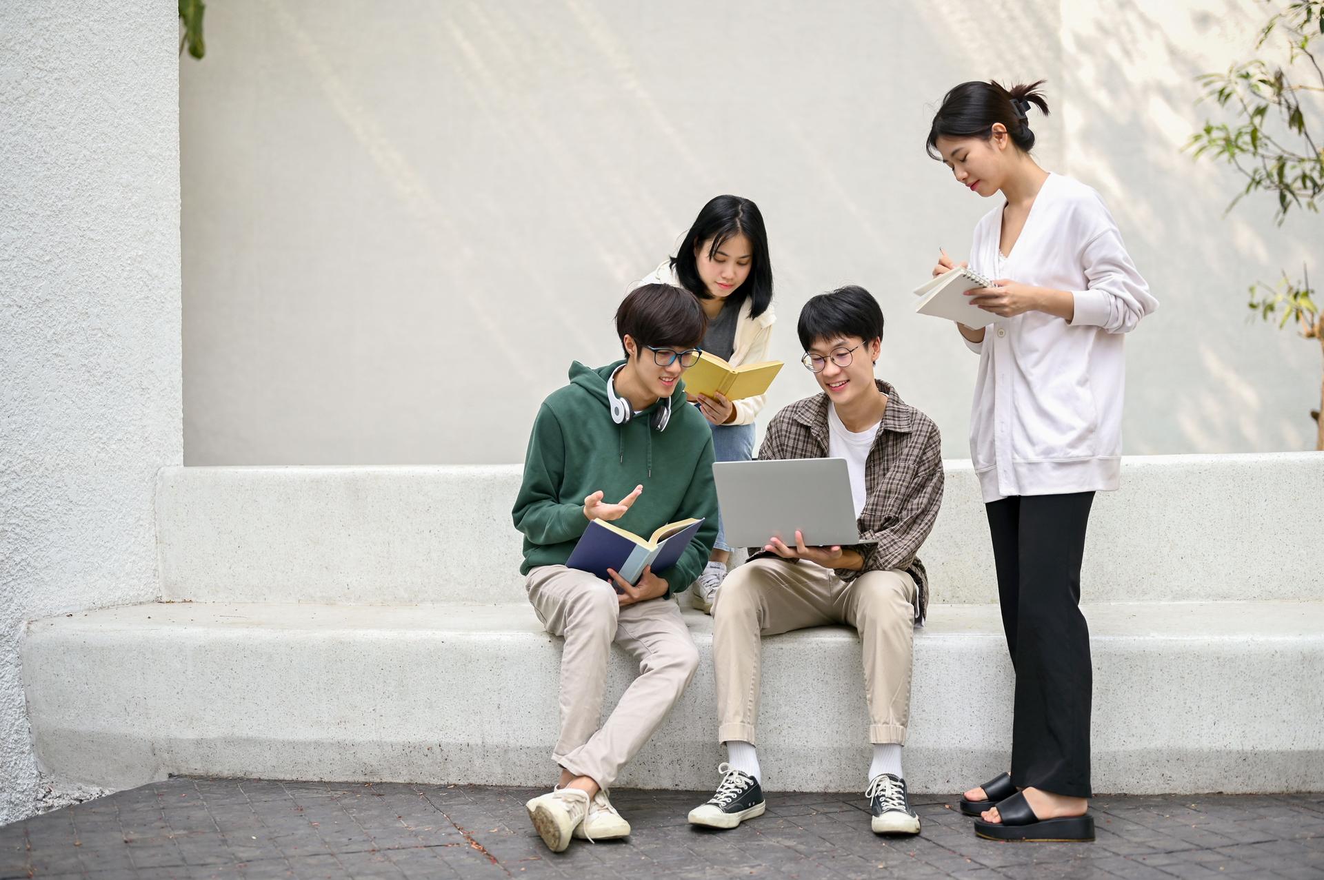 Group of Asian college students working on their project at a campus relaxation area together.